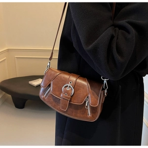 Detail of vintage brown saddle bag with large silver horseshoe buckle and side zippers