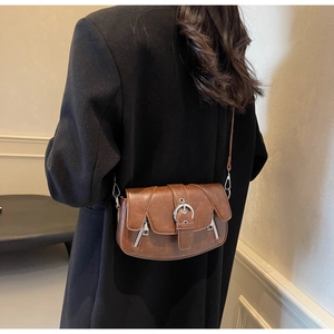 Brown vintage saddle bag with silver ring buckle shown on a model's black jacket