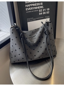 Sac fourre-tout en nylon gris à pois noirs et nœuds sur une table métallique