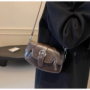 Detail of vintage dark brown leather saddle bag with silver hardware on black coat