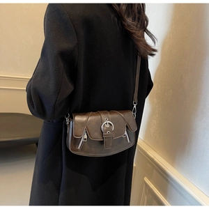 Macro detail of vintage dark brown saddle bag with silver buckle and leather texture