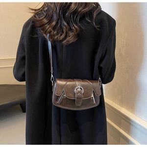 Detailed close-up of dark brown vintage saddle bag featuring silver metal buckle accents