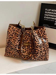Leopard print tote bag with gold chain handles and leather straps on marble surface