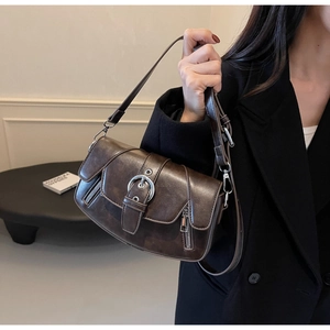 Deep brown retro saddle bag on model wearing a black blazer for a modern aesthetic look