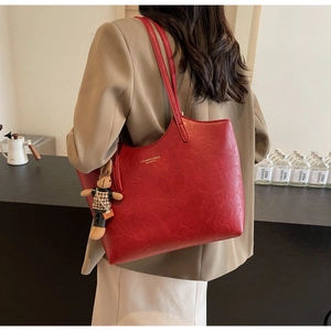 Close-up of red textured tote bag with a checkered bunny charm on a model