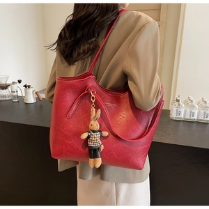 Detail of red PU leather tote bag with gold text and a cute bunny plush keychain