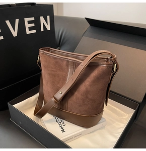 Close-up of brown suede bucket bag featuring leather trim and premium gold hardware