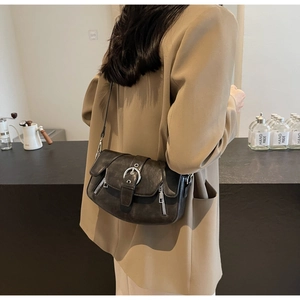 Detail view of a vintage black saddle bag with metallic buckle and zipper accents