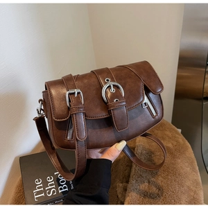 Close-up of vintage brown saddle bag showing PU leather texture and silver buckle detail