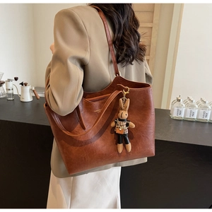Detail of retro brown tote bag with cute rabbit pendant and textured PU material