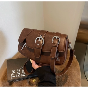 Detail of brown vintage saddle bag with decorative straps and silver metal hardware