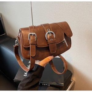 Close-up of vintage brown leather saddle bag with silver buckles and fine textures