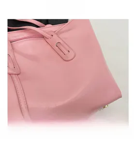 Detail of pink glossy tote bag showing leather texture and gold metal feet on bottom