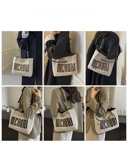 Detail view of large canvas tote bag with brown straps and stylish metal chain handles