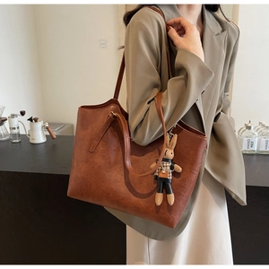 Close-up of brown tote bag with leather texture and cute bunny doll charm accessory