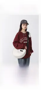 White large nylon crescent bag with wide black strap and matching mini pouch on model