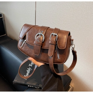 Detail of vintage brown saddle bag showing silver buckles and textured leather finish