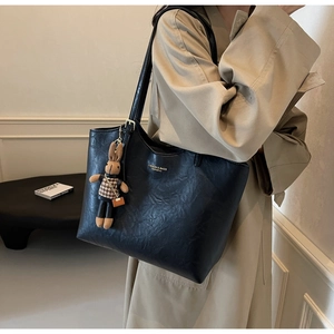 Detail of black PU leather tote bag with rabbit charm and gold brand lettering on body