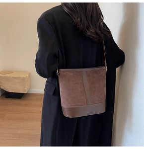 Detail of dark brown bucket bag with contrast suede and smooth leather stitching texture