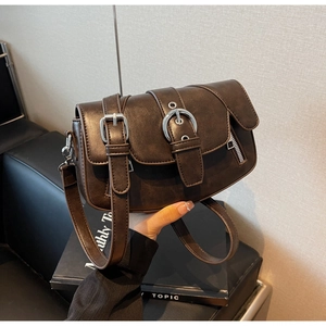 Detail of dark brown vintage saddle bag featuring metallic silver ring and strap texture