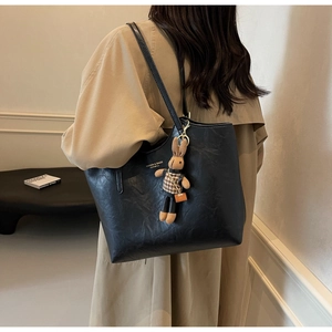 Black tote bag with rabbit pendant detail and textured finish shown on shoulder