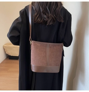 Brown frosted bucket bag with adjustable leather strap shown on black coat