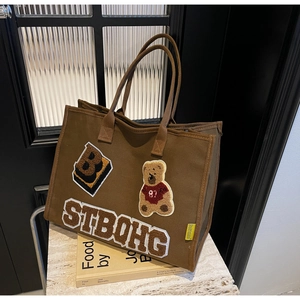 Close-up of brown canvas tote bag featuring bear embroidery and retro patch detailing