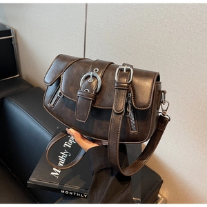 Detail of dark brown vintage saddle bag featuring dual silver buckles and zipper accents