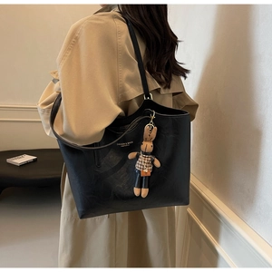 Detail of minimalist black faux leather tote bag with a cute rabbit doll pendant