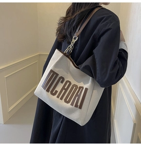 Side view of a large canvas tote bag with brown leather trim and MICAORI lettering