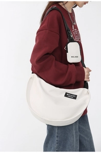 Detail view of large white nylon canvas crescent bag with a matching mini pouch charm