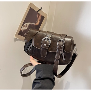 Detail of dark brown vintage saddle bag featuring metallic buckles and zipper accents