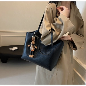 Close-up of large black tote bag featuring a cute rabbit charm and textured PU leather