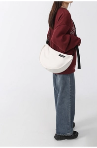 Detail view of the white nylon crescent bag showing the adjustable black shoulder strap