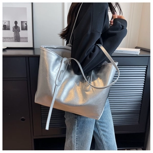 Silver metallic tote bag with wrinkled texture worn by model in a minimalist setting