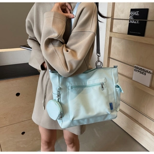Detail of mint green nylon tote bag featuring a round coin purse and adjustable strap