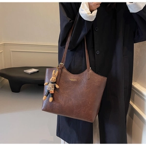 Detail of dark brown leather tote bag with a cute plaid rabbit charm on the shoulder strap