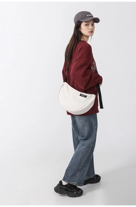 Detail of white nylon canvas crossbody bag with adjustable strap and brand label