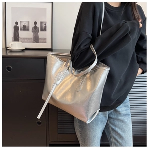 Detail of silver metallic tote bag featuring glossy texture and minimalist slim straps