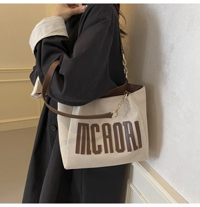 Detail of canvas tote bag showing high-density texture and leather chain strap