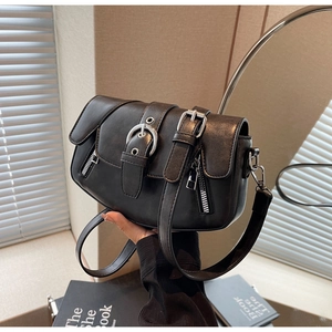 Close-up of black leather saddle bag with silver buckles and natural shadow detail