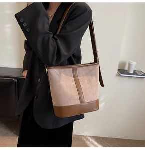 Detail of a two-tone bucket bag featuring suede texture and smooth leather shoulder strap