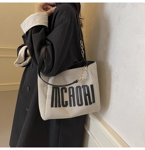 Detail of canvas tote bag with black MCAORI print and golden chain strap link