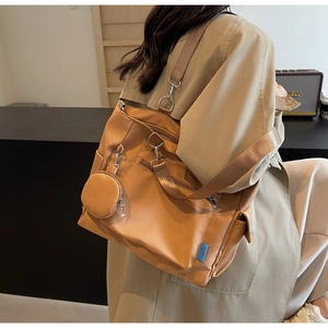 Close-up of brown nylon tote bag featuring multi-pocket zippers and small round coin purse