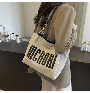 Detailed shot of an off-white canvas tote bag featuring black MCROAI letter stitching