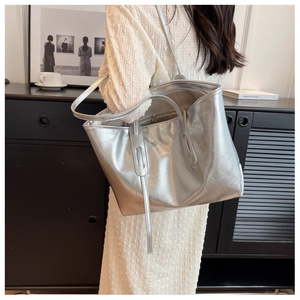 Silver metallic tote bag showing side view with thin shoulder straps on a female model
