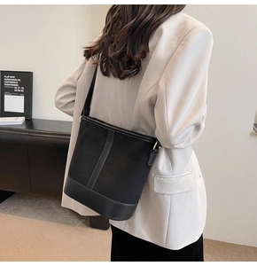 Side view of a large black bucket bag with leather trim on a model for daily commute