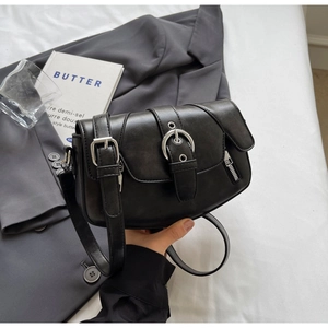 Detail of a vintage black matte leather saddle bag with a large silver buckle and side zipper