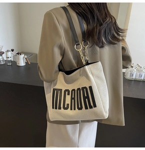 Detail of canvas tote bag with black MCAORI print and leather gold chain strap