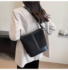 Chic black bucket bag detail showing matte suede and leather patchwork with golden hardware